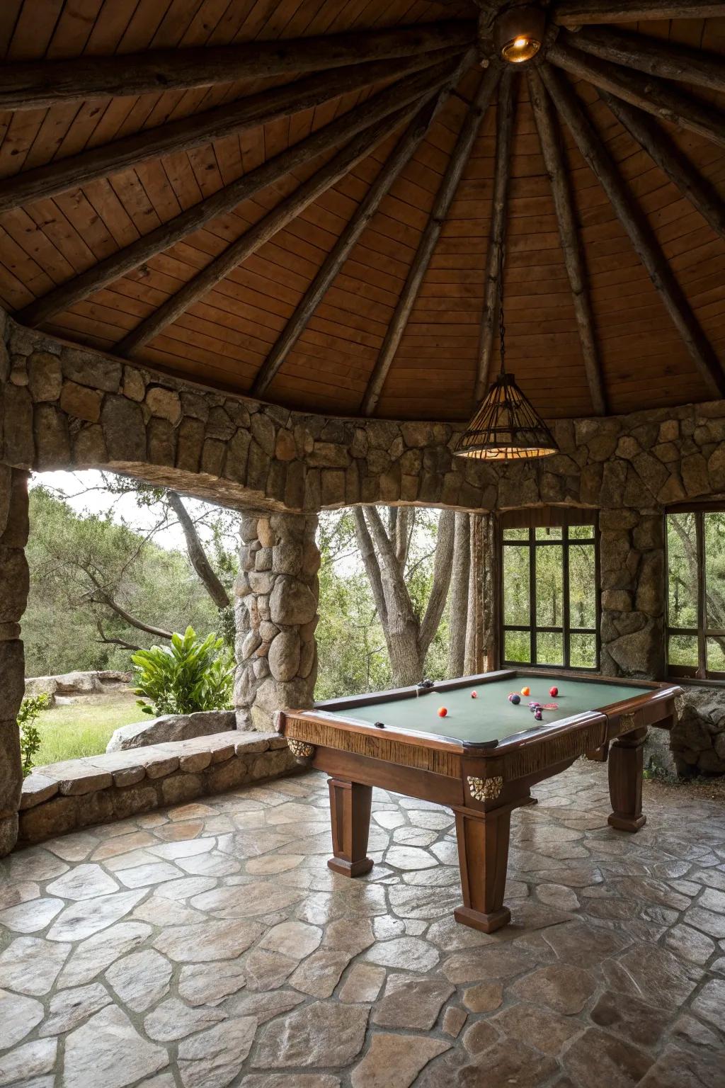 An earthy stone gazebo housing a game table in a natural landscape.